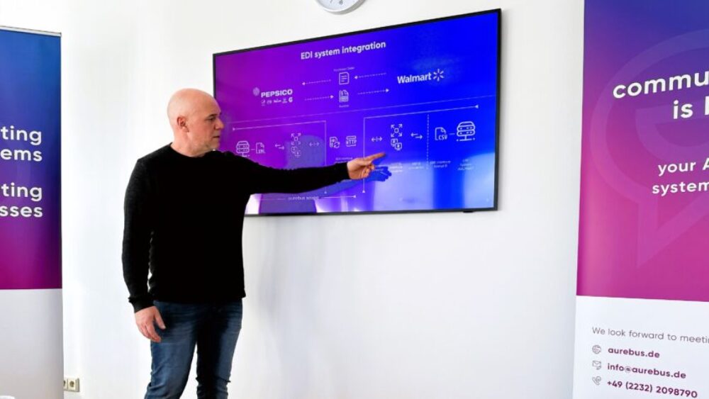 Ein Mann präsentiert etwas vor einem Bildschirm