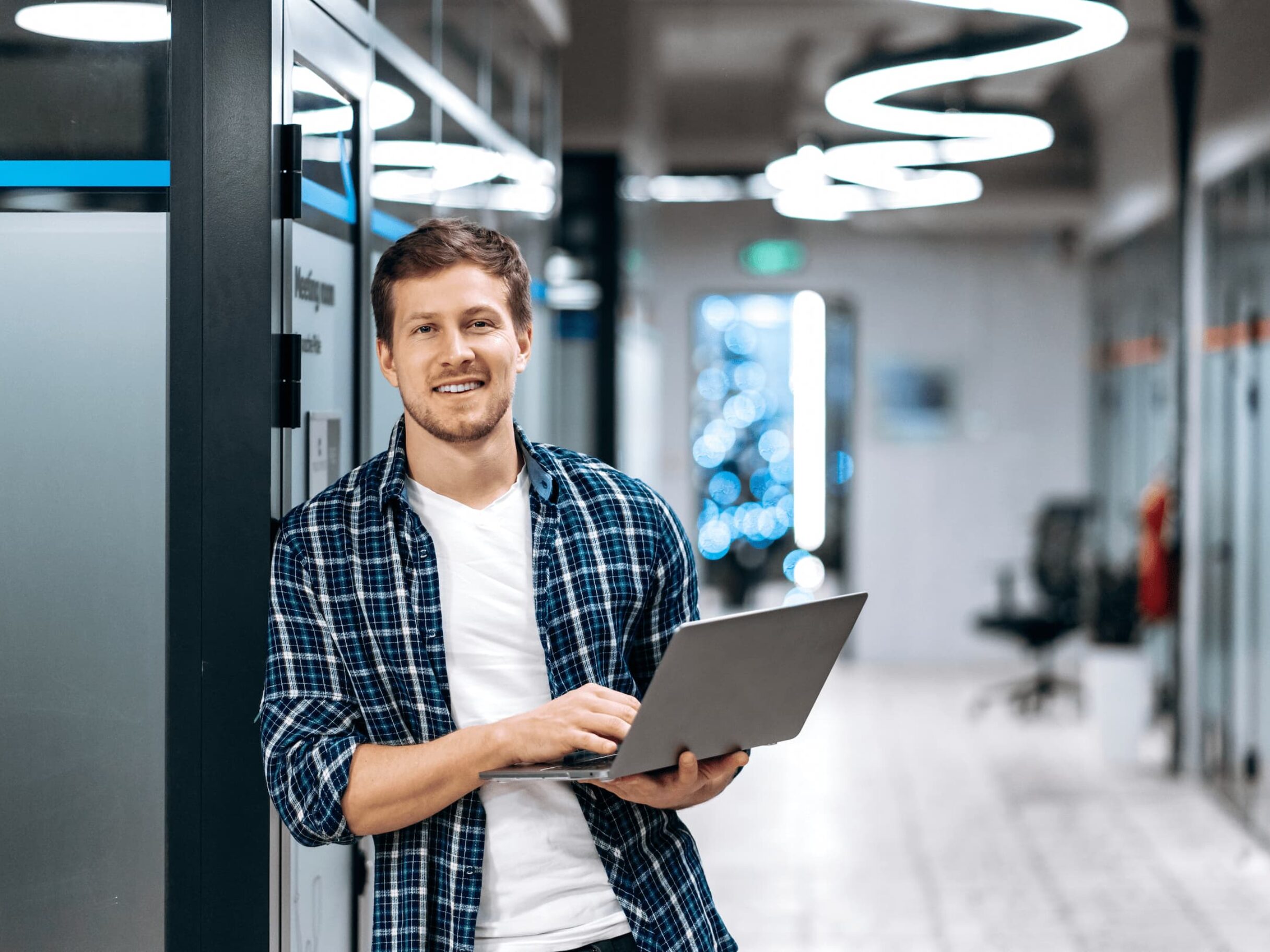 Man mit Laptop lacht in die Kamera