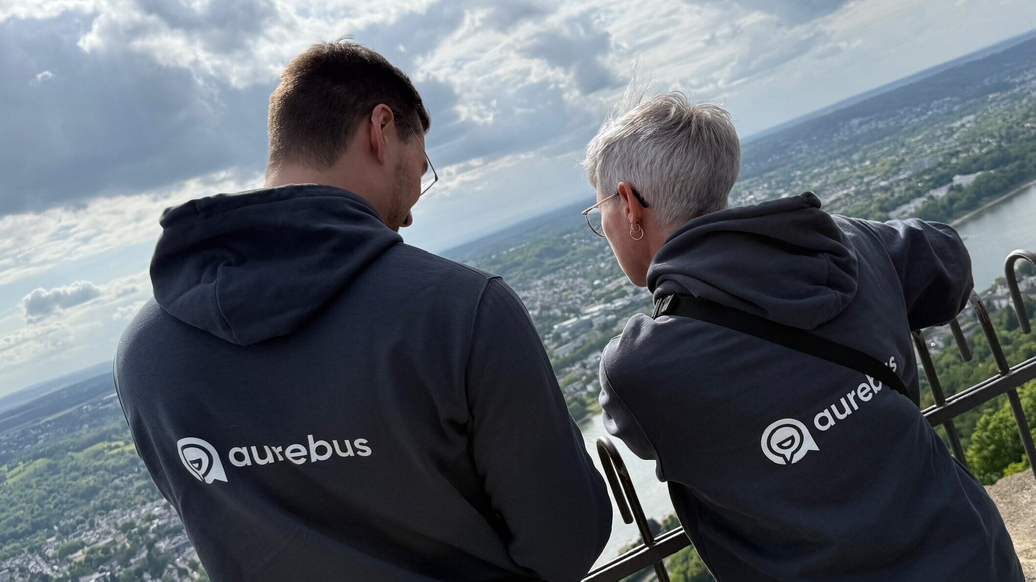 zwei Menschen mit dem Rücken zur Kamera mit Pullis und dem aurebus Logo
