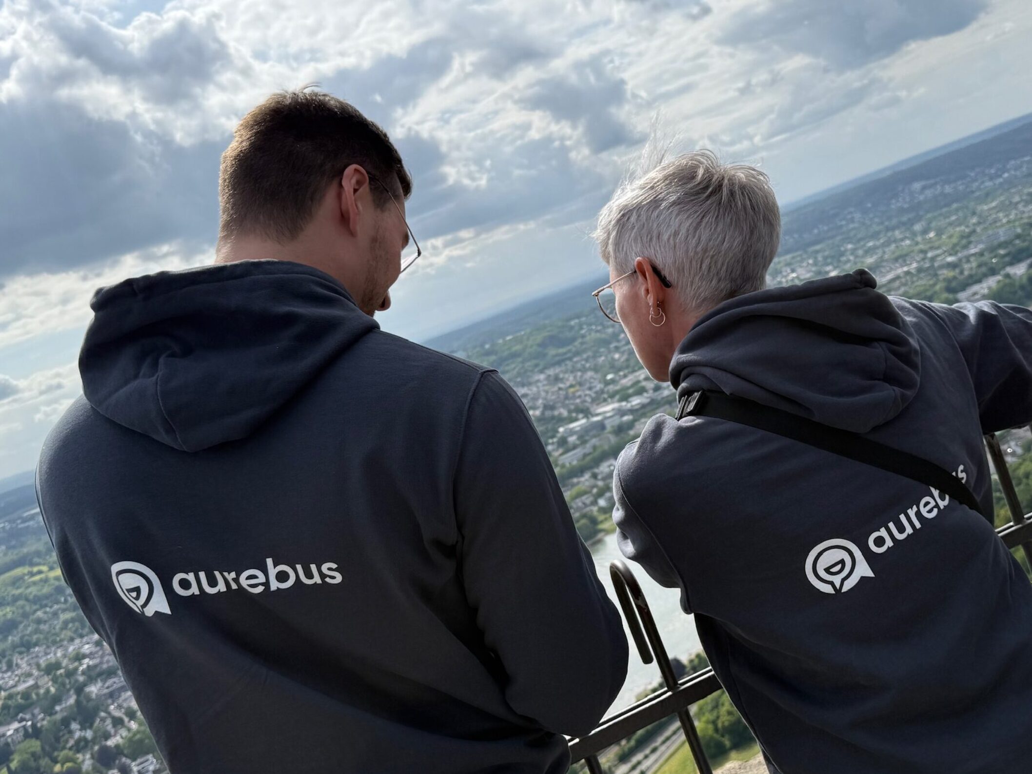 zwei Menschen mit dem Rücken zur Kamera mit Pullis und dem aurebus Logo