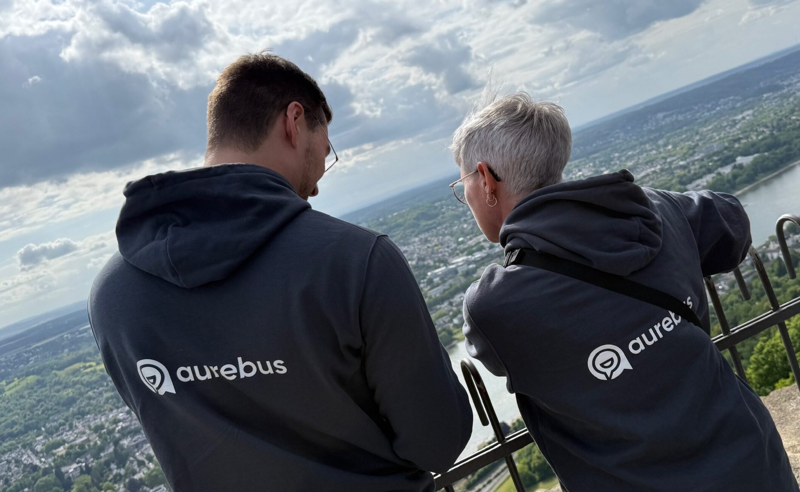 zwei Menschen mit dem Rücken zur Kamera mit Pullis und dem aurebus Logo